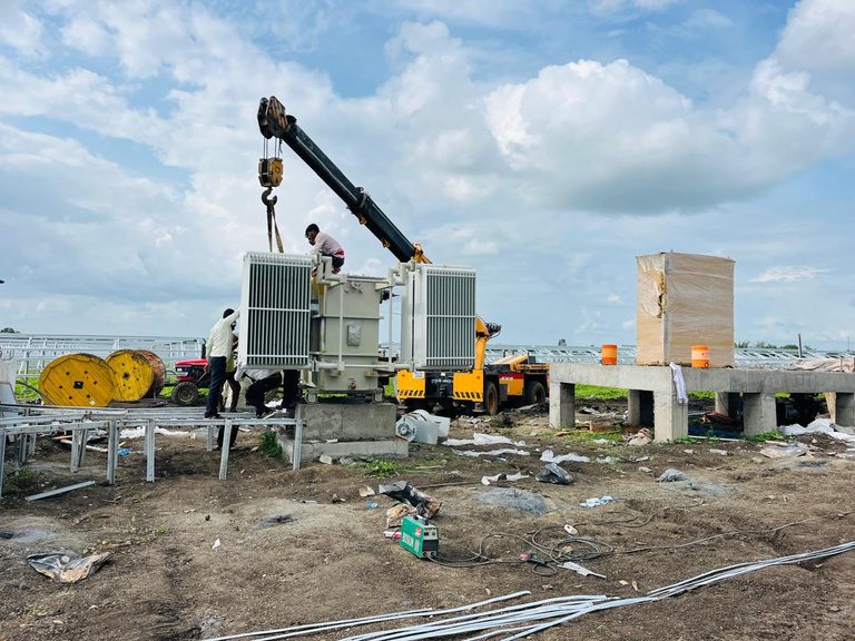 Crane lifting a transformer at a solar project site